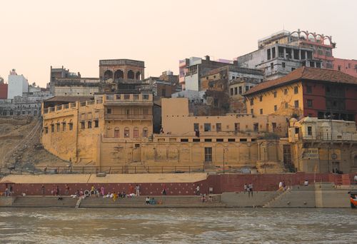 Free View of ancient ghats and architecture along the Ganges River in Varanasi, India at sunset. Stock Photo