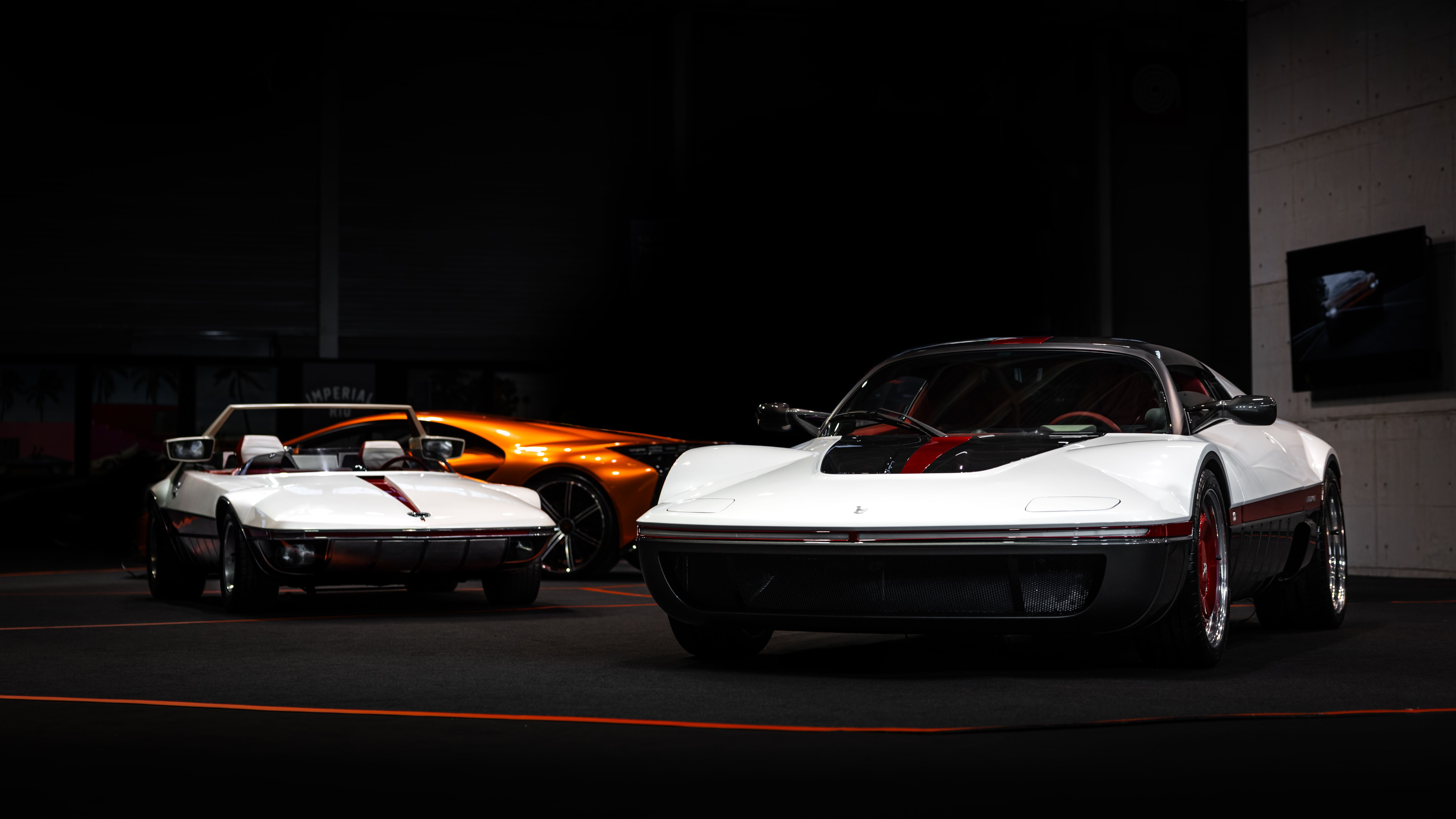Vintage and modern sports cars on display in an indoor showroom.