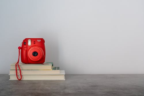 Red Instant Camera On Top Of A Book