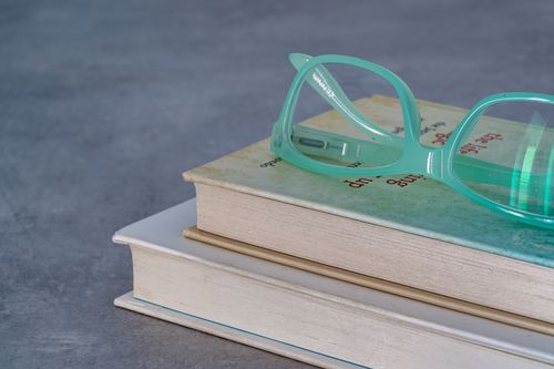 Free Close-up of stacked books with teal eyeglasses on top, perfect for reading themes. Stock Photo