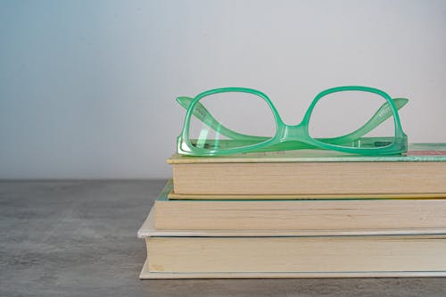 Green Framed Eyeglasses On Top Of A Book