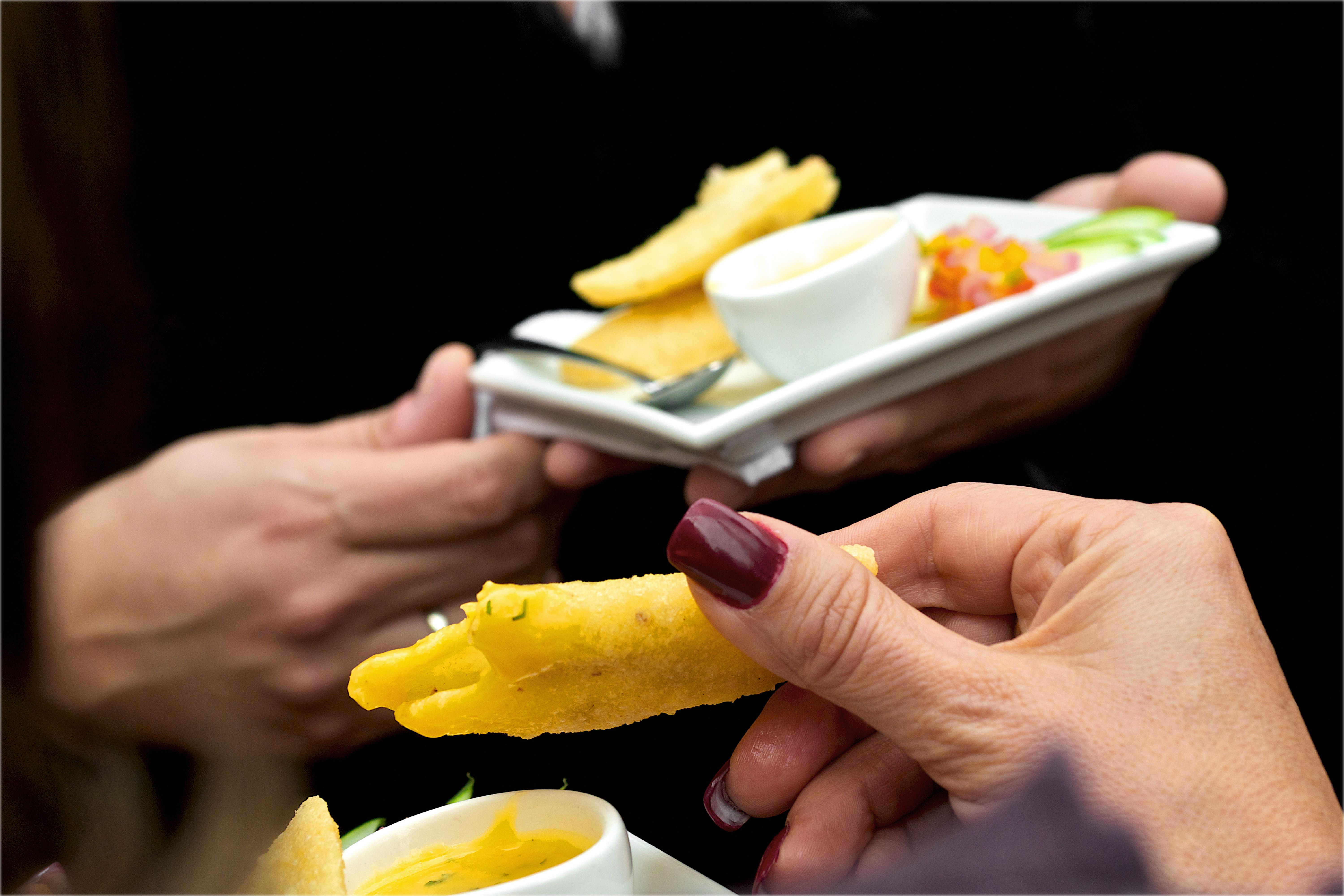 A close-up of party appetizers served on plates at a gathering, with dipping sauce.