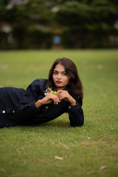 Free A woman in a denim outfit lying on grass in an autumn park. Stock Photo