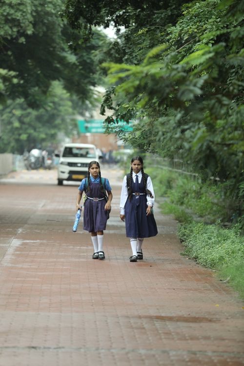 Free Two schoolgirls in uniform walking along a tree-lined street in Raipur, India. Stock Photo