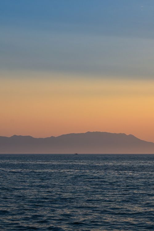 Free A tranquil sunset over the Aegean Sea viewed from Enez, Türkiye, with distant mountains under pastel skies. Stock Photo