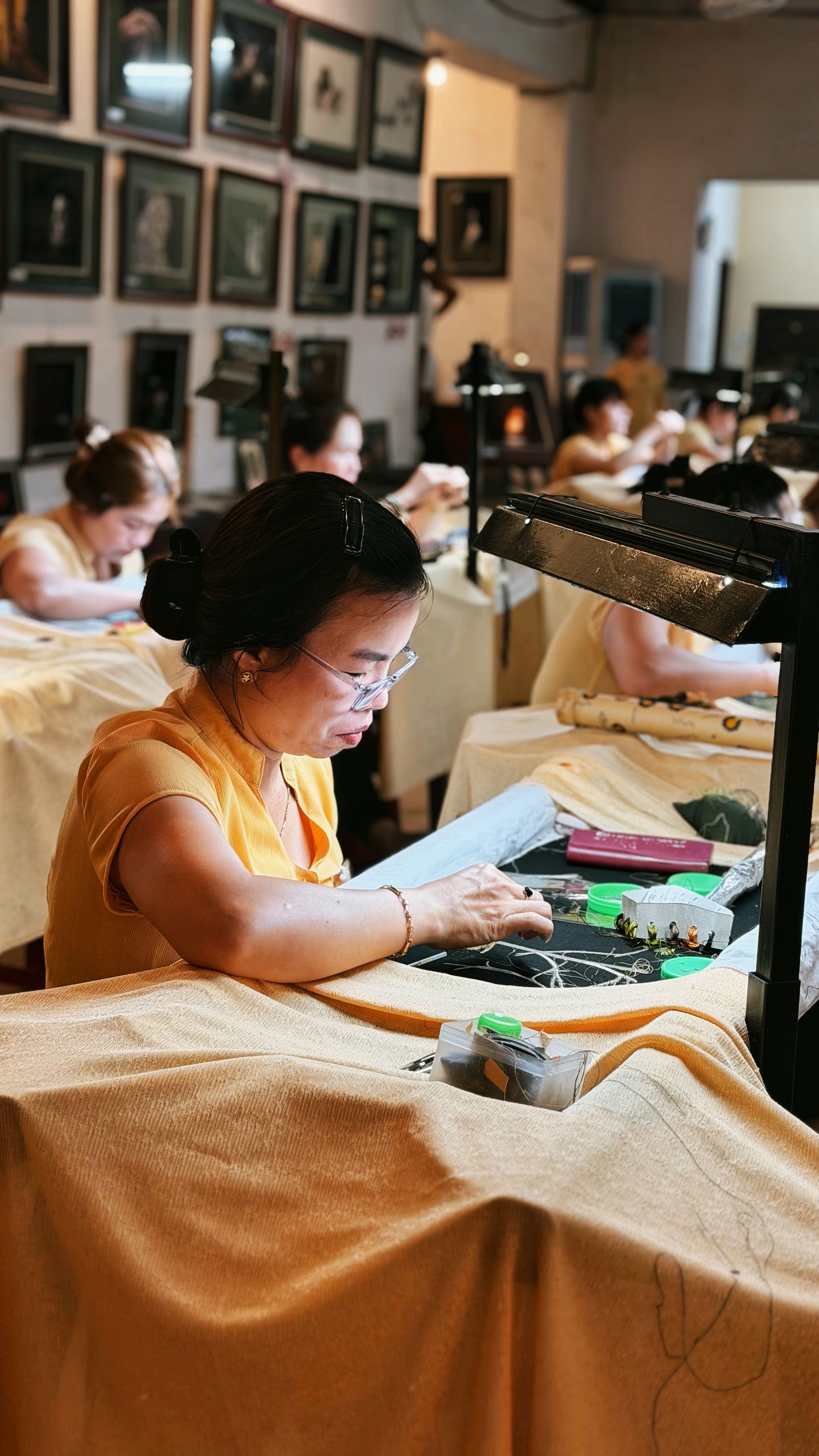 Female artisan focused on silk embroidery in a traditional workshop in Da Nang, Vietnam.