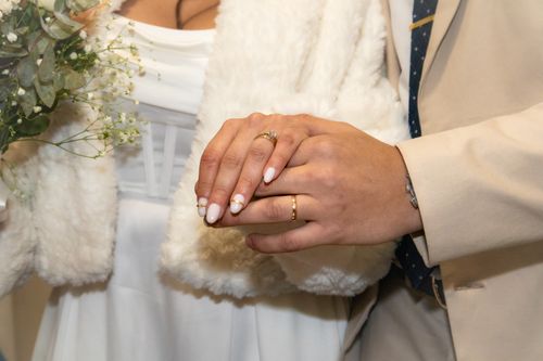 Free Close-up of a bride and groom's hands showing wedding rings and elegant attire. Stock Photo