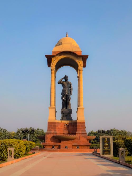 Free A statue of a soldier saluting, surrounded by greenery in a New Delhi monument. Stock Photo