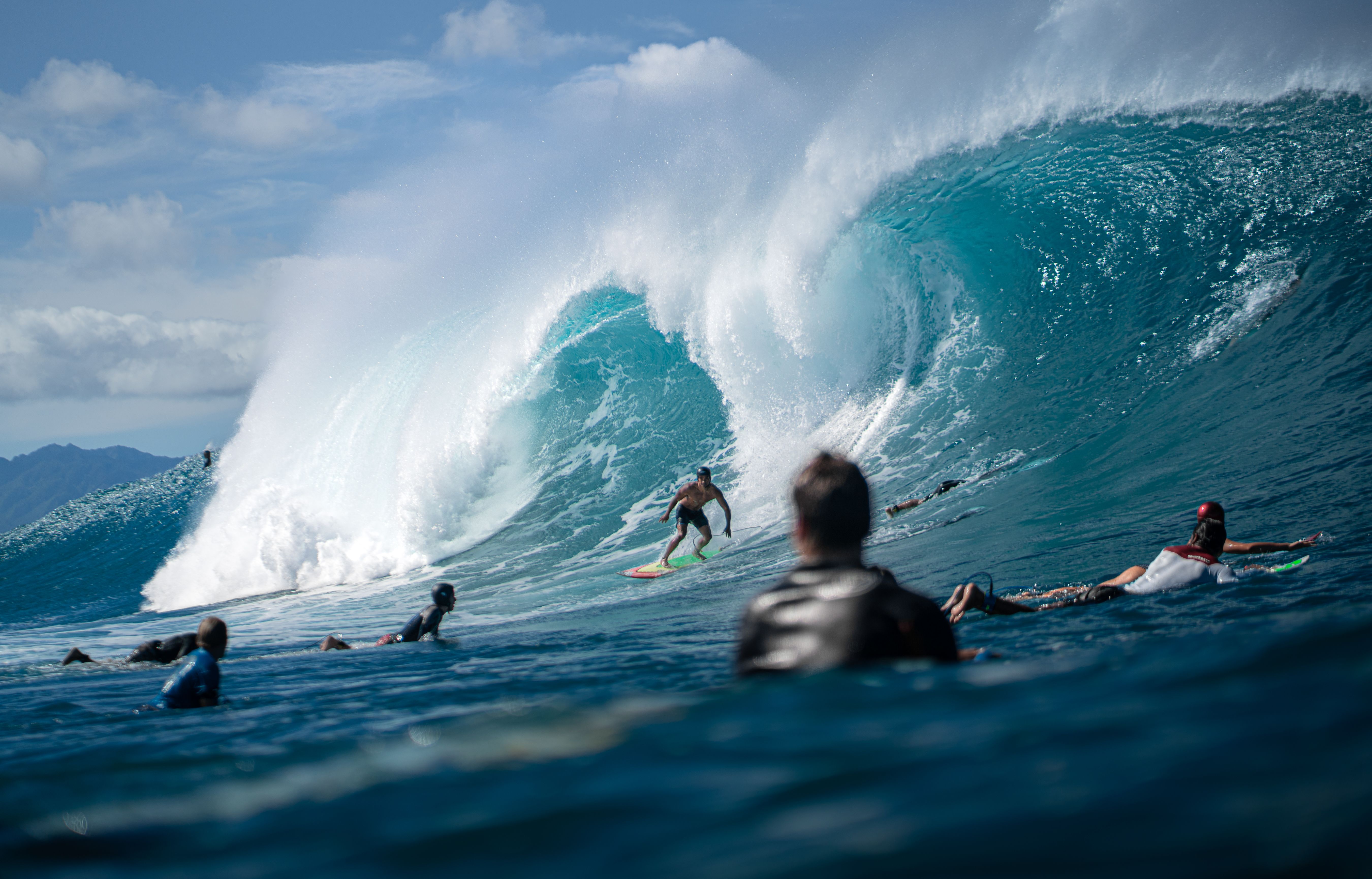 Dynamic surfing scene capturing surfers riding massive waves off the coast of Hawaii.