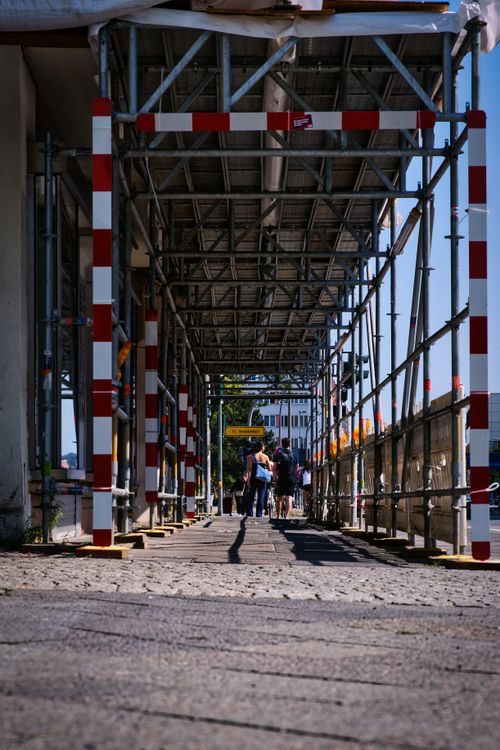 Free People walking under scaffolding in a Berlin street, showcasing urban construction. Stock Photo