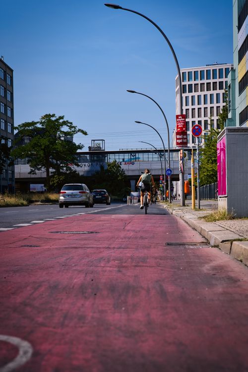 Free Diverse cityscape featuring a cyclist on a distinctive red bike path in Berlin, Germany. Stock Photo