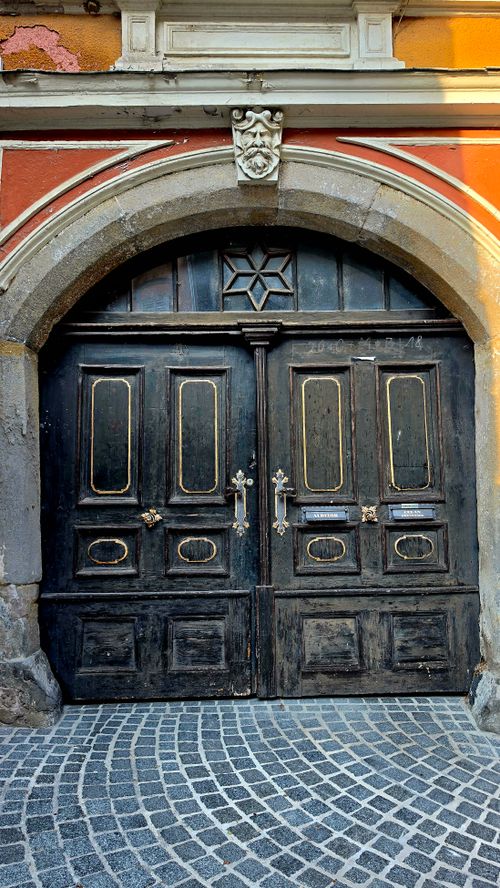 Free A vintage wooden door set in an ornate arched stone frame, showcasing historical architecture. Stock Photo