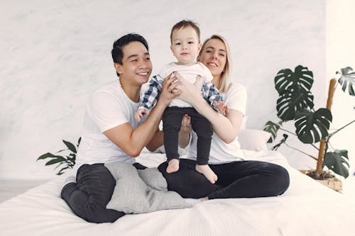 Man And Woman In White Shirt Holding Their Child