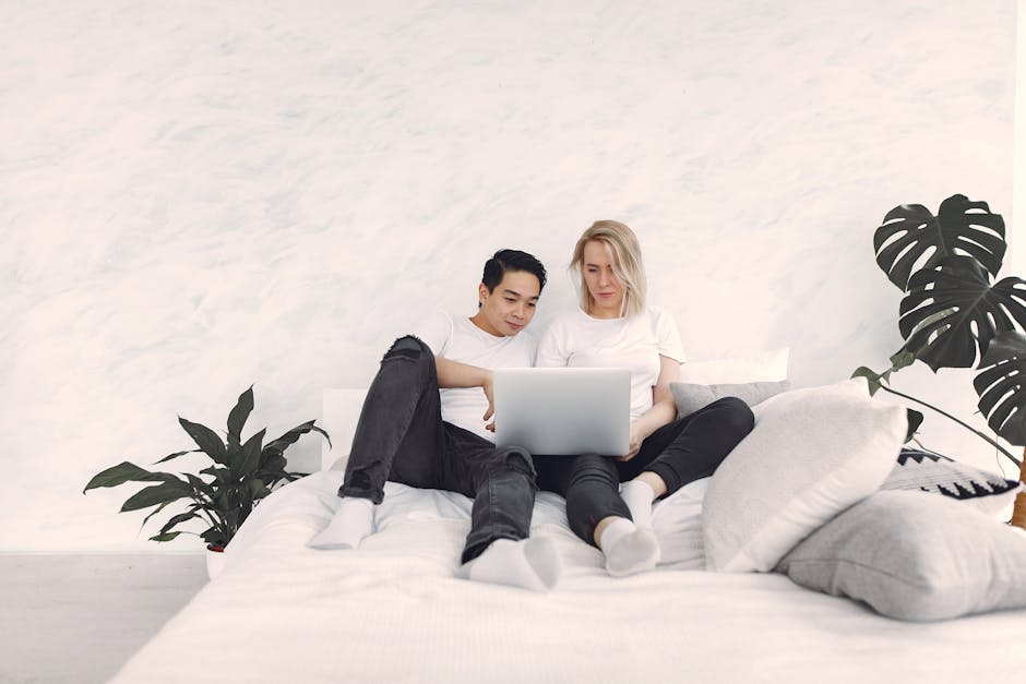 What CertiPUR-US Foam Testing Really Means for Your Mattress A couple lounging on a bed, sharing a laptop in a bright, minimalist bedroom setting.