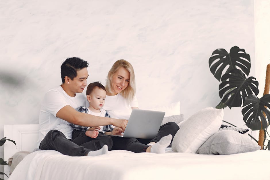 How SNOO Smart Bassinet Rocking Patterns Help Newborns Sleep Longer Overnight A joyful family with a child enjoying time together on a bed, using a laptop indoors.
