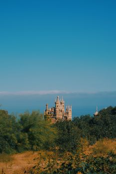 A stunning view of a castle amidst lush greenery under a clear blue sky in Málaga, Spain.