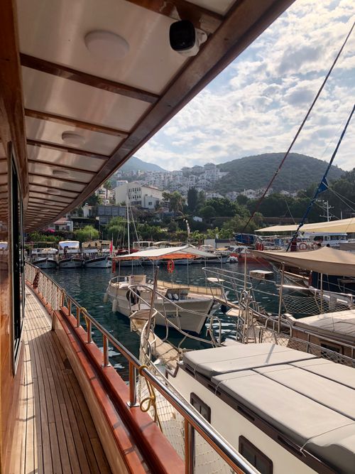 Free A peaceful view of boats docked in a marina with hills in the background during a sunny summer day. Stock Photo