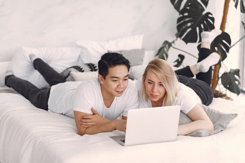 Free Man and Woman on Bed Using Laptop Computer Stock Photo