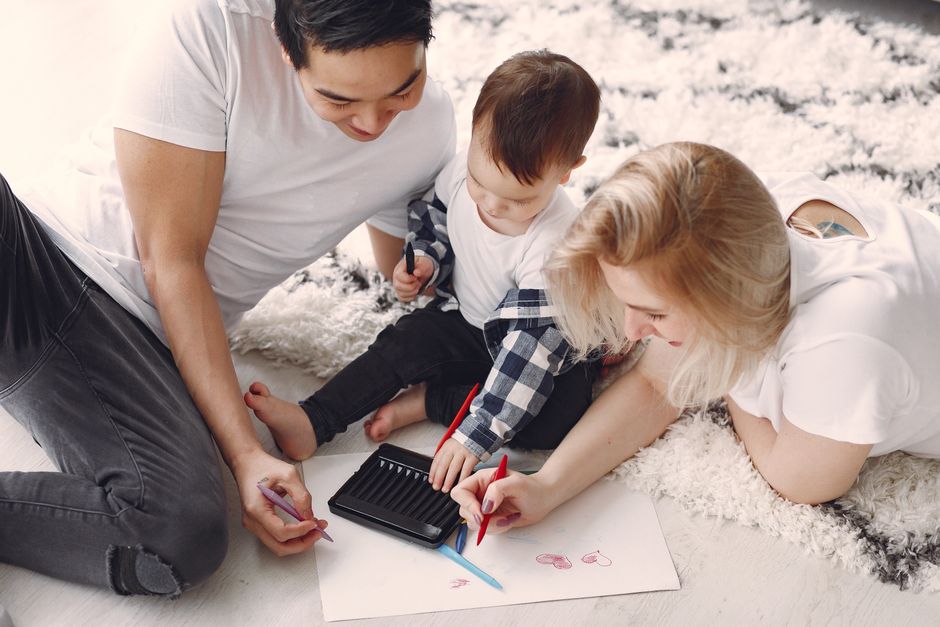 Padres e hijo disfrutando de dibujar juntos en el suelo, creando recuerdos.