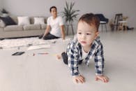 可爱的男婴在地板上爬行，爸爸则在舒适的客厅里看着