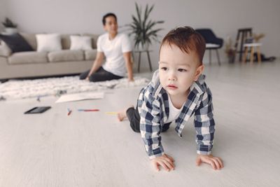 Baby boy crawling across a bright living room floor