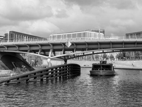Free A monochrome cityscape featuring a modern bridge, boat, and urban architecture. Stock Photo