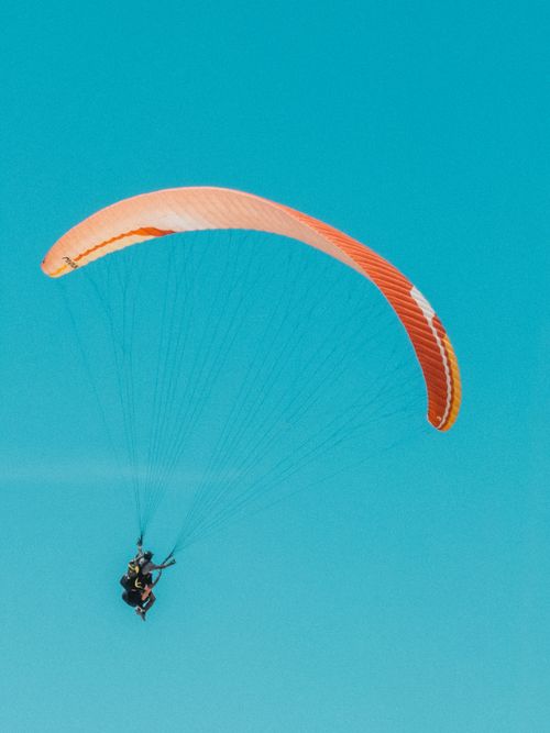 Free A thrilling tandem paragliding experience captured against a bright blue sky, showcasing adventure and freedom. Stock Photo