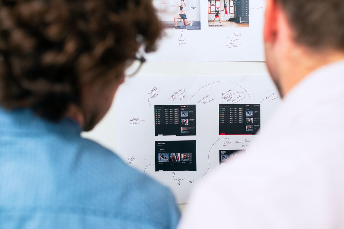 Two professionals brainstorming software development with a whiteboard