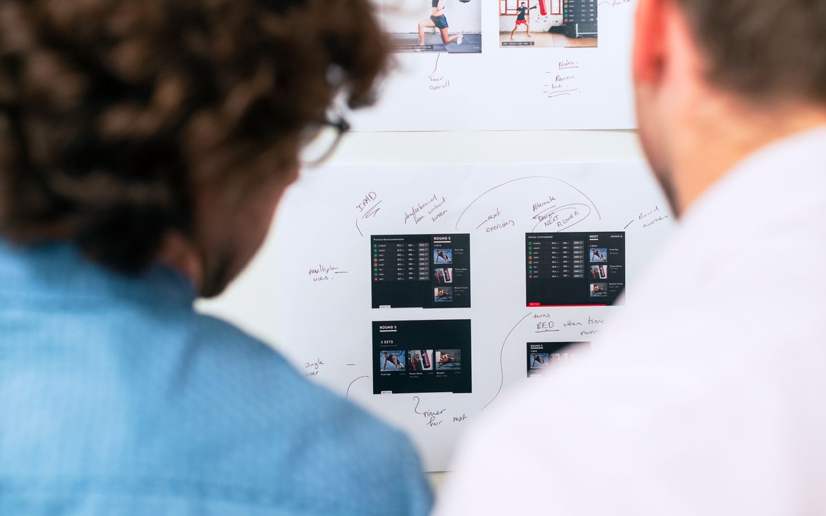 Two business professionals brainstorming and planning software development with a whiteboard in an office.
