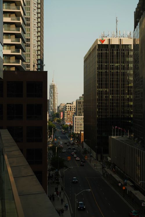 Free Dramatic cityscape featuring tall skyscrapers and a busy urban street at sunset. Stock Photo