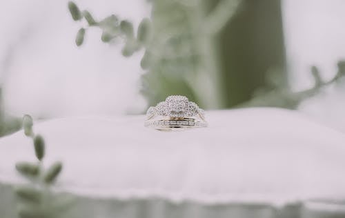 бесплатная Серебряное и золотое кольцо на белом текстиле Стоковое фото
