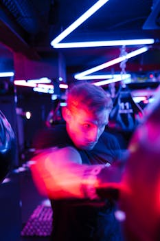 A determined boxer striking a punching bag under vibrant neon lights in a gym.