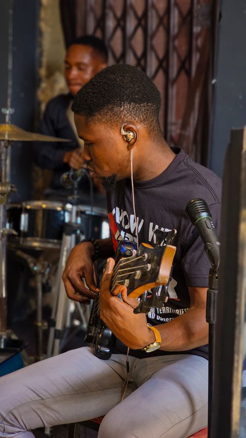 Free Two young musicians play guitar and drums indoors, creating a vibrant musical atmosphere. Stock Photo