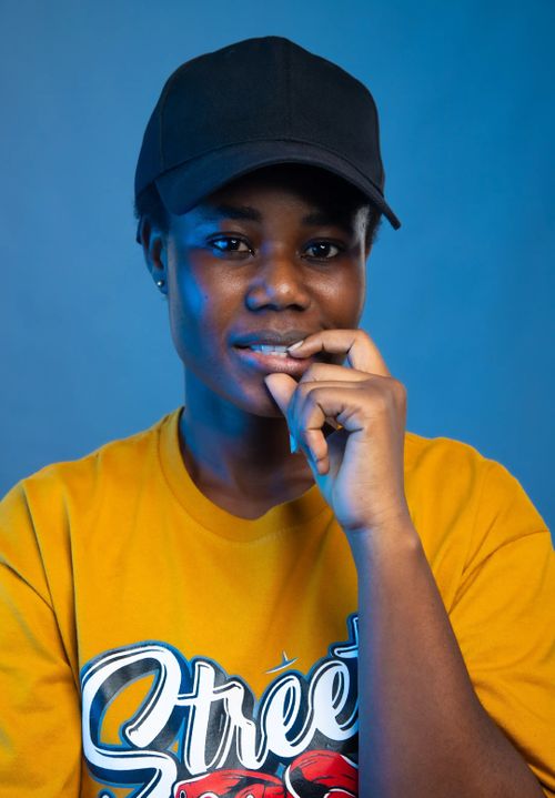 Free Portrait of a confident teenager in a yellow shirt and black cap on a blue background. Stock Photo