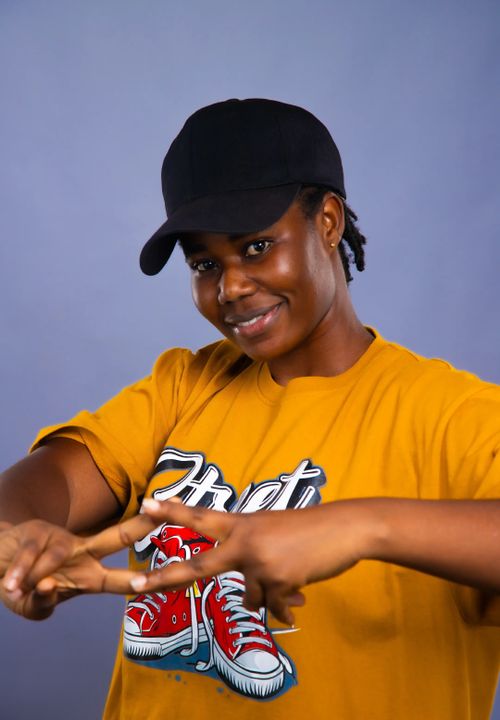 Free Smiling woman in a casual outfit making a playful gesture wearing a black cap. Stock Photo
