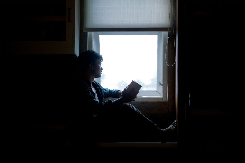 person reading near window indoors