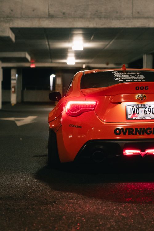 Free Rear view of an orange sports car in a dimly lit urban parking garage. Stock Photo
