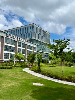 Contemporary office building surrounded by lush greenery under a blue sky in Shanghai.
