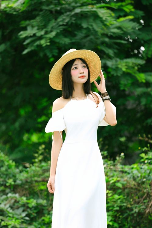 Free Young woman in a white dress with a straw hat enjoying nature in Hanoi, Vietnam. Stock Photo