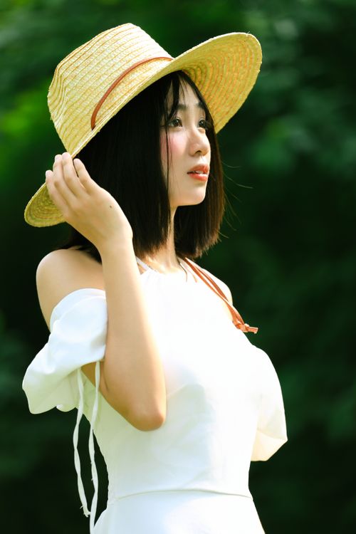 Free A young woman wearing a straw hat enjoying a sunny day outdoors Stock Photo