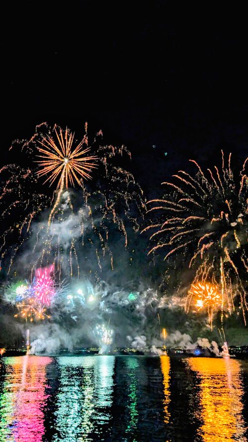 Free Vivid fireworks light up the night sky over Lake Garda, Italy, reflecting beautifully on the water. Stock Photo