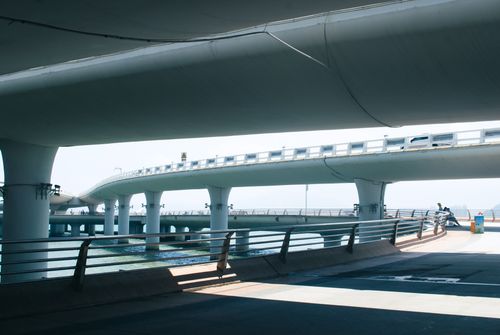 Free Dynamic architectural view of an urban bridge with blue sky and water below. Stock Photo