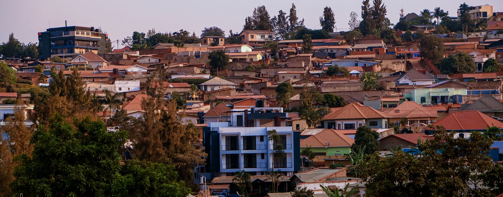 A vibrant panorama of Kigali's residential area showcasing architecture and greenery at sunset.