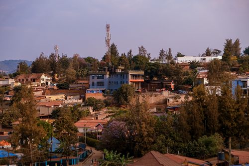 Free A vibrant urban scene showcasing buildings, vegetation, and distant hills under a clear sky. Stock Photo