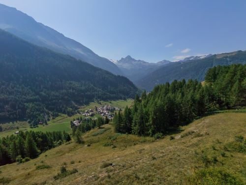 Free Breathtaking aerial view of an alpine valley and village in summer with lush greenery. Stock Photo