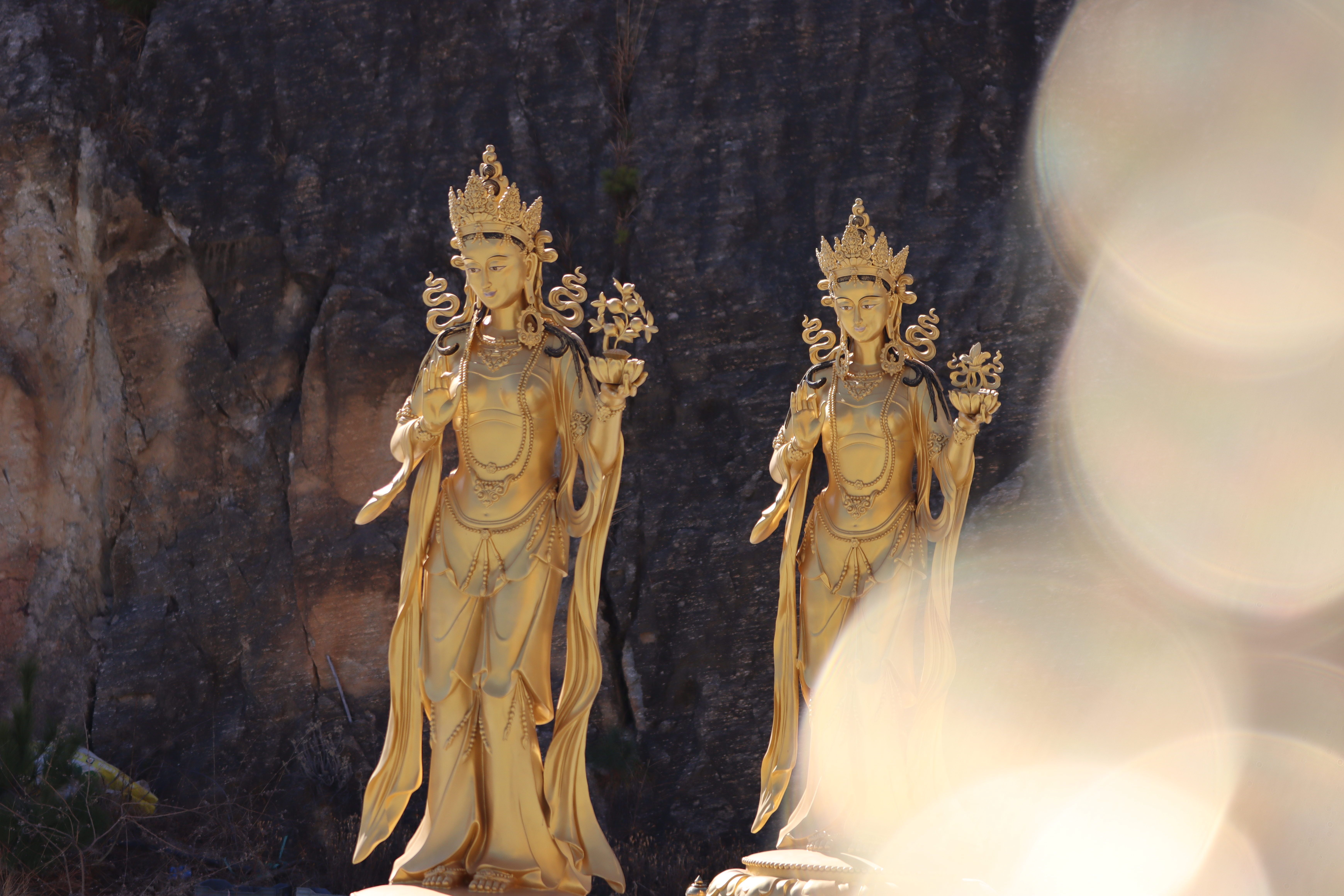 Two exquisite golden Buddha statues set against a natural stone backdrop, radiating serenity and peace.