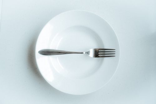 Free A minimalist setting with a fork centered on a white plate, perfect for food-related themes. Stock Photo