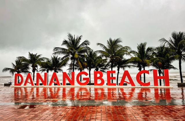 A stormy day at Danang Beach, Vietnam with palm trees and reflective wet tiles. — arriving in Da Nang