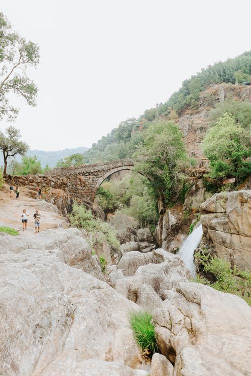 Free Explore a scenic stone bridge and waterfall in Montalegre, Portugal, surrounded by lush greenery. Stock Photo