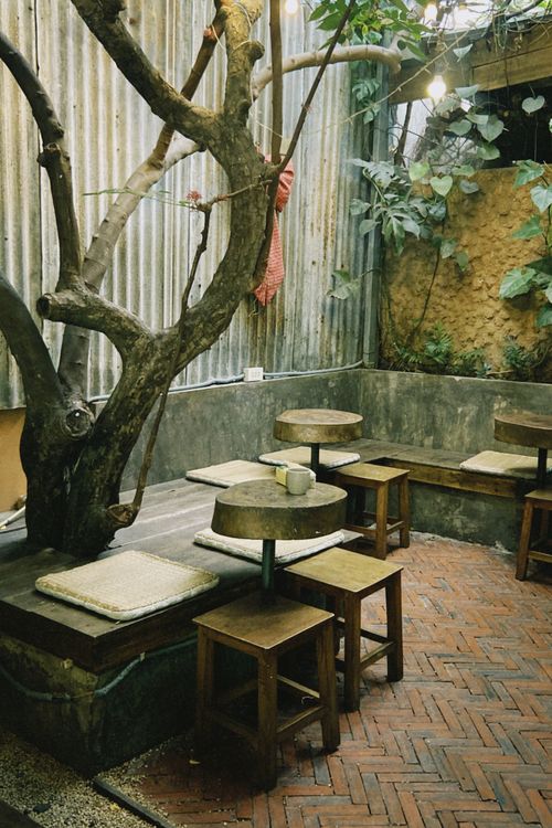 Free Charming outdoor seating area with rustic wooden furniture and greenery in a Ho Chi Minh City cafe. Stock Photo